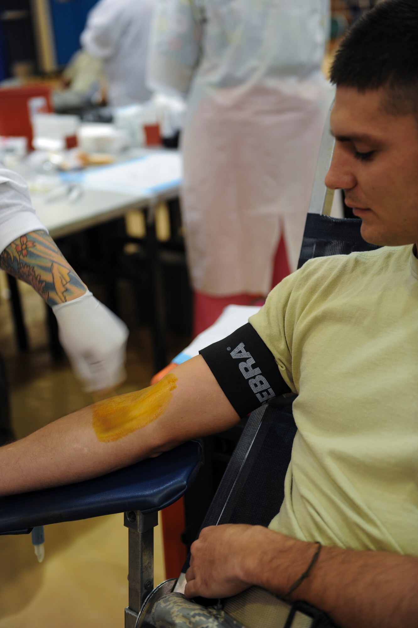 U.S. Air Force Senior Airman Joseph Mount, 23d Civil Engineer Squadron structure journeyman, watches as his arm is stained with iodine before donating blood at Moody Air Force Base, Ga., Sept. 4, 2013. The collection technician cleans the area for 30 seconds and lets it dry before finding a vein to start the donation. (U.S. Air Force photo by Airman Alexis Grotz/Released)