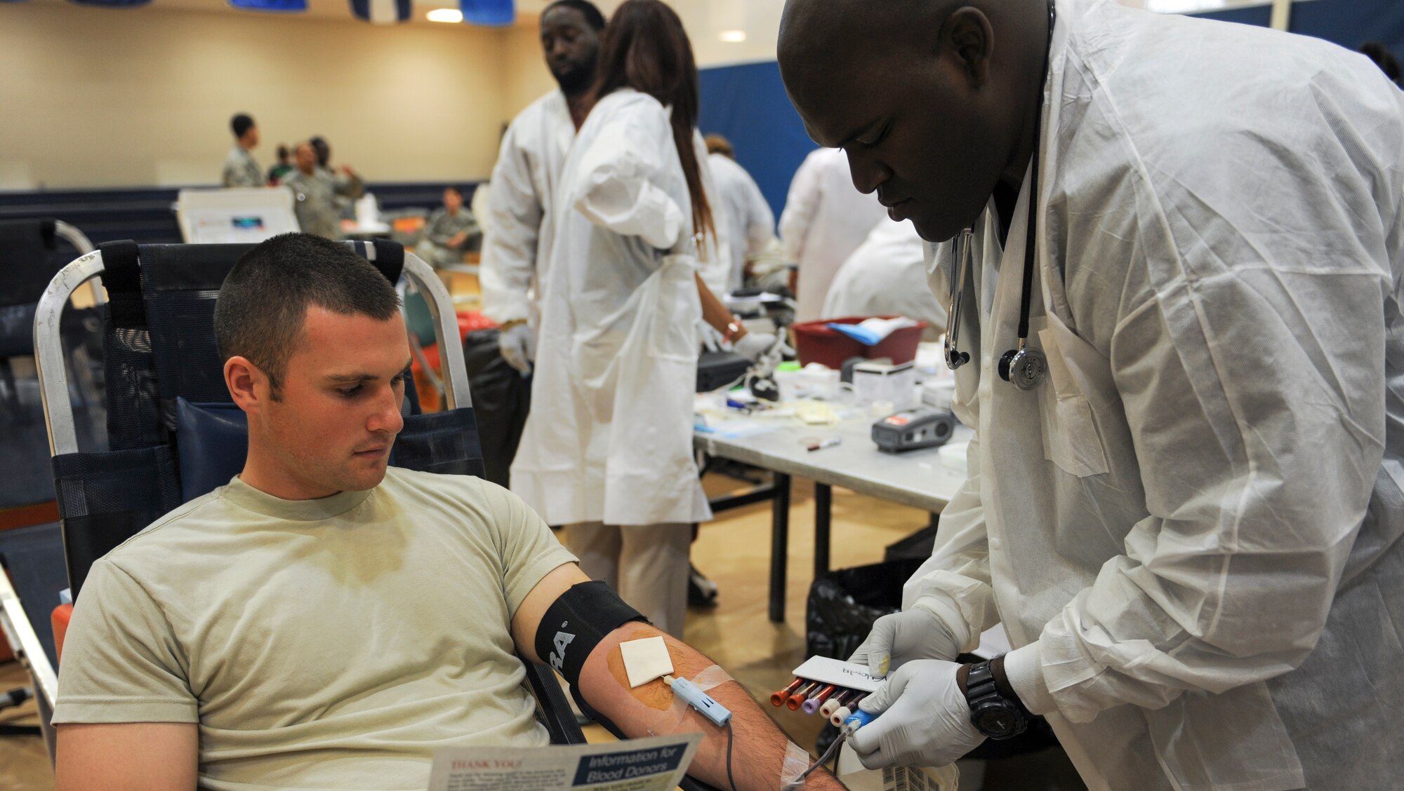 U.S. Air Force Airman 1st Class Jonathan Miller, 824th Base Defense Squadron fireteam member, watches as Derek Sorrell, Red Cross collection technician, fills specimen tubes after a blood donation at Moody Air Force Base, Ga., Sept. 4, 2013. Miller was one of an estimated 70 Airmen who donated blood. (U.S. Air Force photo by Airman Alexis Grotz/Released)