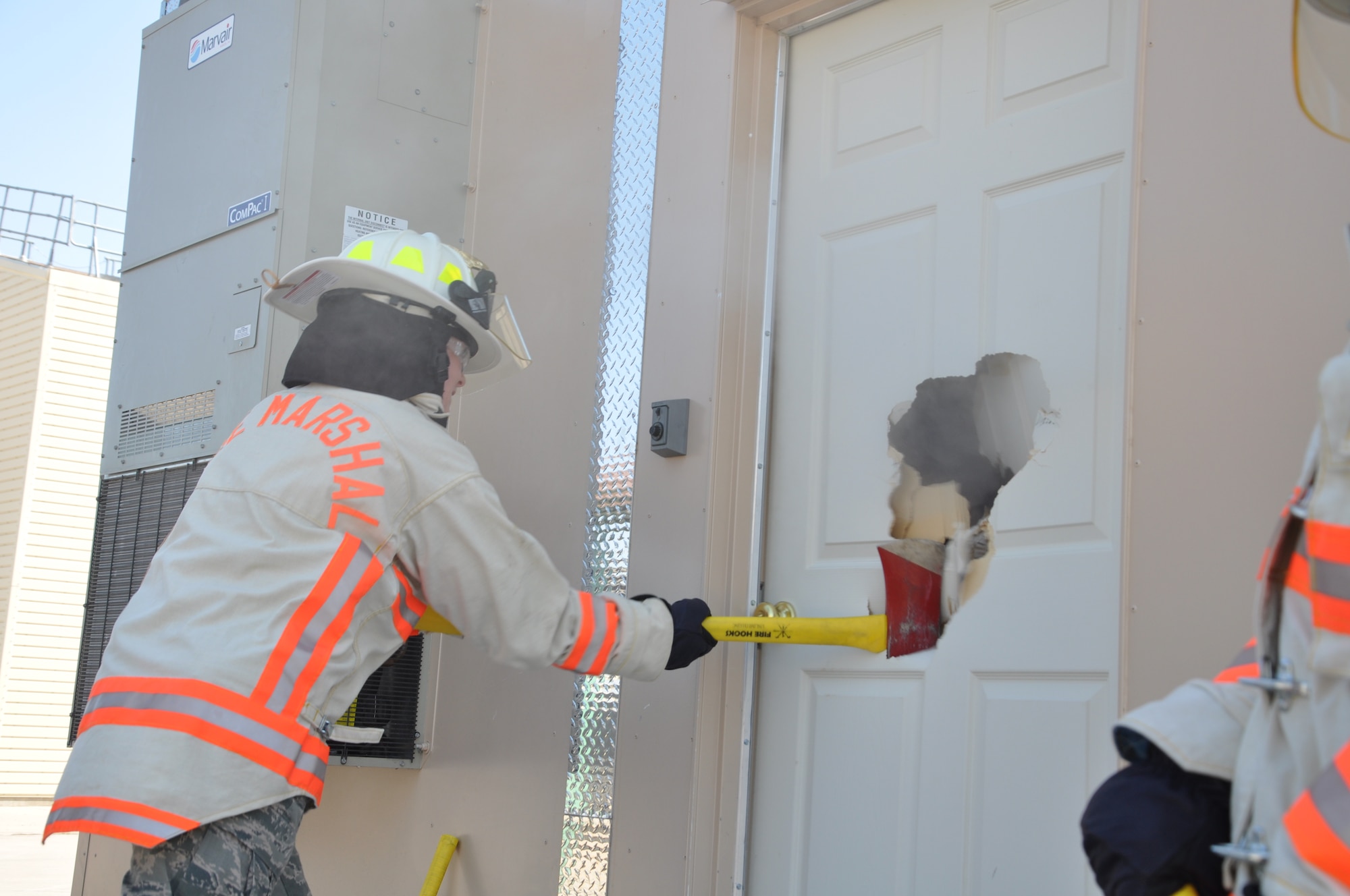 GOODFELLOW AIR FORCE BASE, Texas- Col. Kimberlee Joos , 17th Training Wing Commander, breaks open a door to the newest structural fire trainer at the Defense Department Louis F. Garland Fire Academy during the dedication of the trainer Aug. 30. The trainer was built to provide students training in search and rescue, opening ventilation and more. (U.S. Air Force photo/ Airman 1st Class Erica Rodriguez)