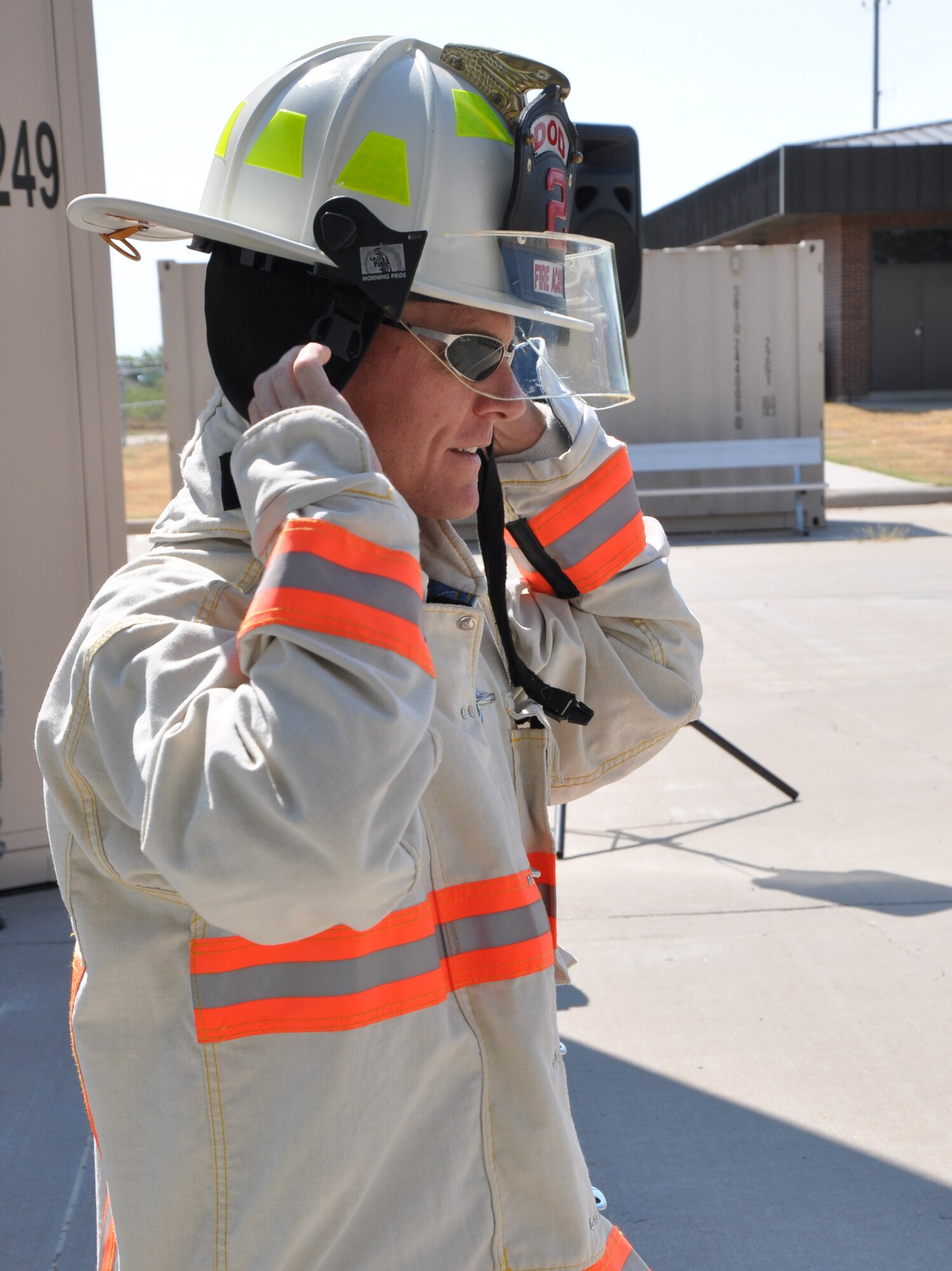 GOODFELLOW AIR FORCE BASE, Texas – Col. Brendan Harris, 17th Training Group Commander, equips a firefighting helmet at the 312th Training Squadron new firefighter trainer dedication Aug. 30. After donning all the protect gear, Col Harris and Col. Kimberlee Joos, 17th Training Wing Commander, broke down a door at the end of the official dedication for the new fire trainer. (U.S. Air Force photo/ Airman 1st Class Joshua Edwards)