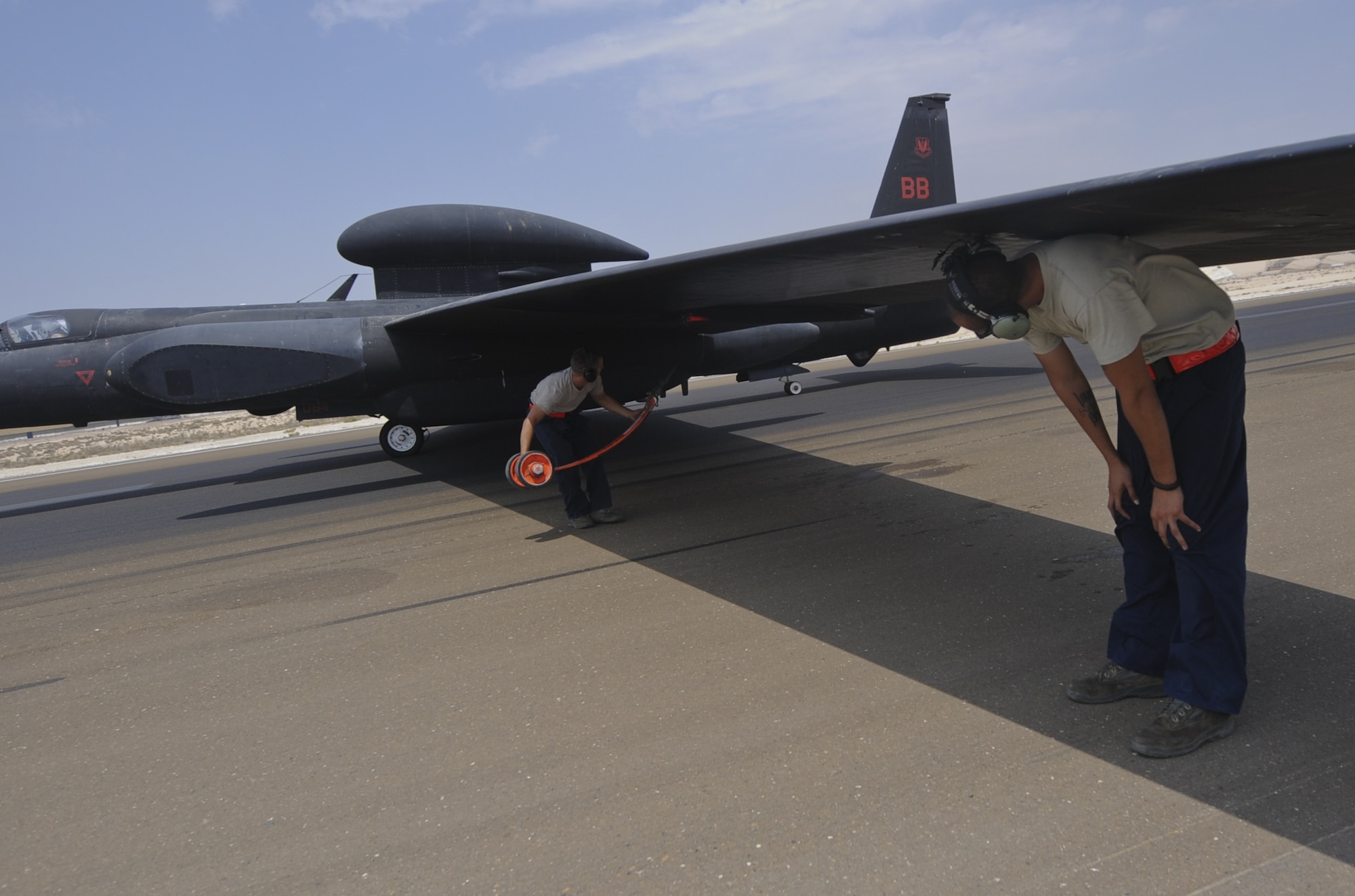 U.S. Air Force Airman 1st Class Kyle Yoder, 380th Expeditionary Aircraft Maintenance Squadron U-2 Aircraft Maintenance Unit crew chief, left, places an auxiliary landing gear, or pogo, underneath the wing of a U-2 Dragon lady as U.S. Air Force Senior Airman Michael Espinoza, 380th EAMXS U-2 AMU crew chief holds the wing in place at an undisclosed location in Southwest Asia Aug. 27, 2013. The pogo team is required to place an auxillary landing gear under each wing so the aircraft can taxi back to the hangar safely. (U.S. Air Force photo by Staff Sgt. Jacob Morgan)