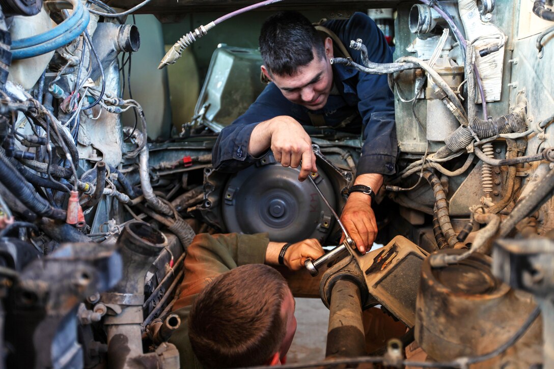 U.S. Marine Corps Cpl. Jose L. Polanco, top, loosens a drive shaft mount on a vehicle with the assistance of U.S. Marine Corps Lance Cpl. Tanner M. Jones, bottom, during Exercise Koolendong 13 on Bradshaw Field Training Area, Australia, Sept. 1, 2013. Polanco, a heavy equipment mechanic, and Jones, a light-armored vehicle mechanic, are assigned to Combat Logistics Battalion 31, 31st Marine Expeditionary Unit.