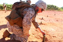 Pfc. Douglas S. Zimmerman places a block of TNT on the ground Aug. 27 during a demolitions training evolution at a demo range in the Central Training Area. The Marines placed 25 blocks of TNT in an interconnected ring of detonation cord, referred to as a "daisy chain." Zimmerman is a combat engineer with 9th ESB.