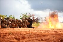 A stack of Marines takes cover behind a protective blanket during an explosion Aug. 28 while completing a demolitions training evolution at a demo range in the Central Training Area. The knowledge of the different types of explosives in urban mobility breaching is vital to combat engineers as they perform a key role in a war-time theater. The Marines are combat engineers with 9th Engineer Support Battalion, 3rd Marine Logistics Group, III Marine Expeditionary Force.