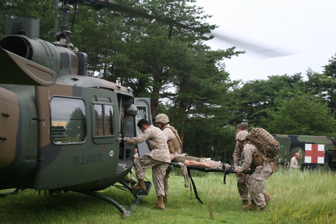 Marines and sailors rush a mock casualty onto a Japan Ground Self-Defense Force helicopter Aug. 31 during medical evacuation training at the Ojojihara Maneuver Area. The training was in preparation for the live-fire artillery scheduled to take place during Artillery Relocation Training Program 13-2. The Marines and sailors are with 1st Battalion, 12th Marine Regiment, currently assigned to 3rd Battalion, 12th Marines, 3rd Marine Division, III Marine Expeditionary Force, under the unit deployment program.