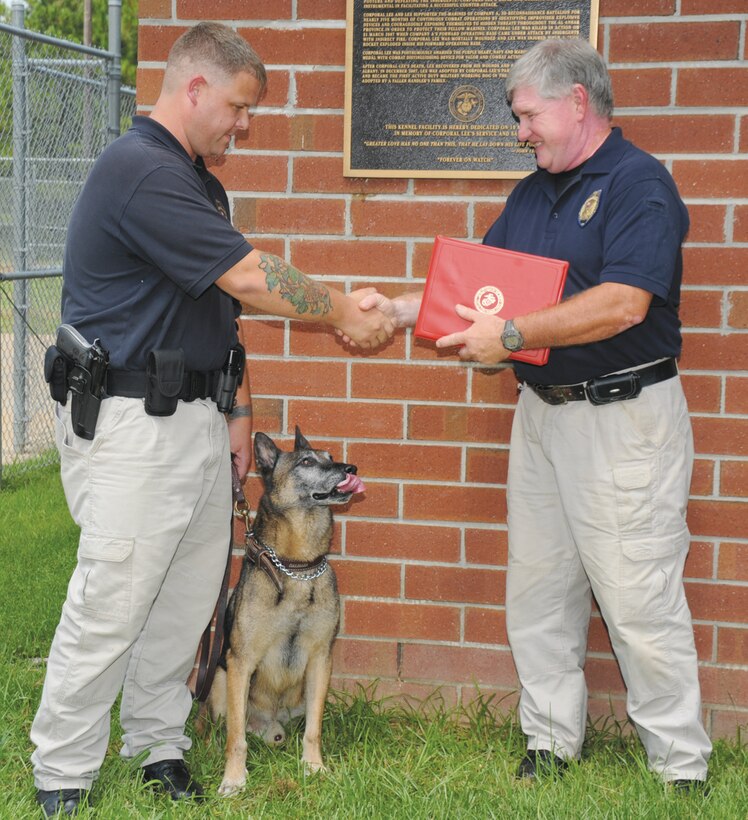 Randy Jack, chief of police, Marine Corps Police Department, right, presents Cpl. Christopher Gurr, Civilian Police Working Dog handler, MCPD, with a certificate for BarrosÕ distinguished service, Tuesday. Barros, a patrol/drug detector dog, retired after seven years during a ceremony at Corporal Dustin Jerome Lee Kennel and Gurr adopted him.