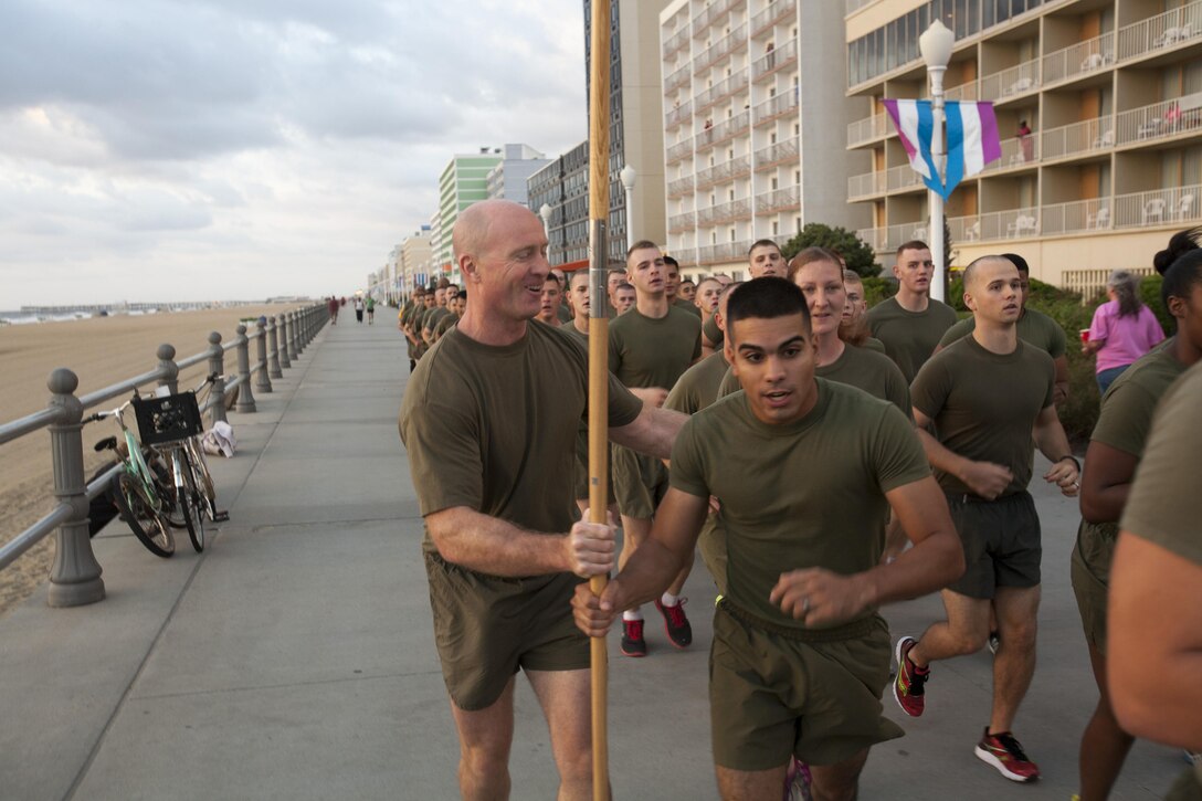 Col. Paul Ryan, commanding officer, Headquarters and Service Battation, U.S. Marine Corps Forces Command, passes the unit guidon to Lance Cpl. Rafael Colon during a formation run along the Virginia Beach Boardwalk Sept. 6. The run was intended to improve the Marines' physical fitness while building esprit de corps and camaraderie. Colon is a data network specialist at MARFORCOM and hails from Philadelphia.