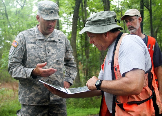 Jim Davis (right), a Vanasse Hangen Brustlin, Inc., project manager, looks on as John Evans, a Norfolk District environmental scientist, shows district commander Col. Paul Olsen maps of proposed future mitigation sites. The sites will offset the loss of stream beds due to changes in water levels.