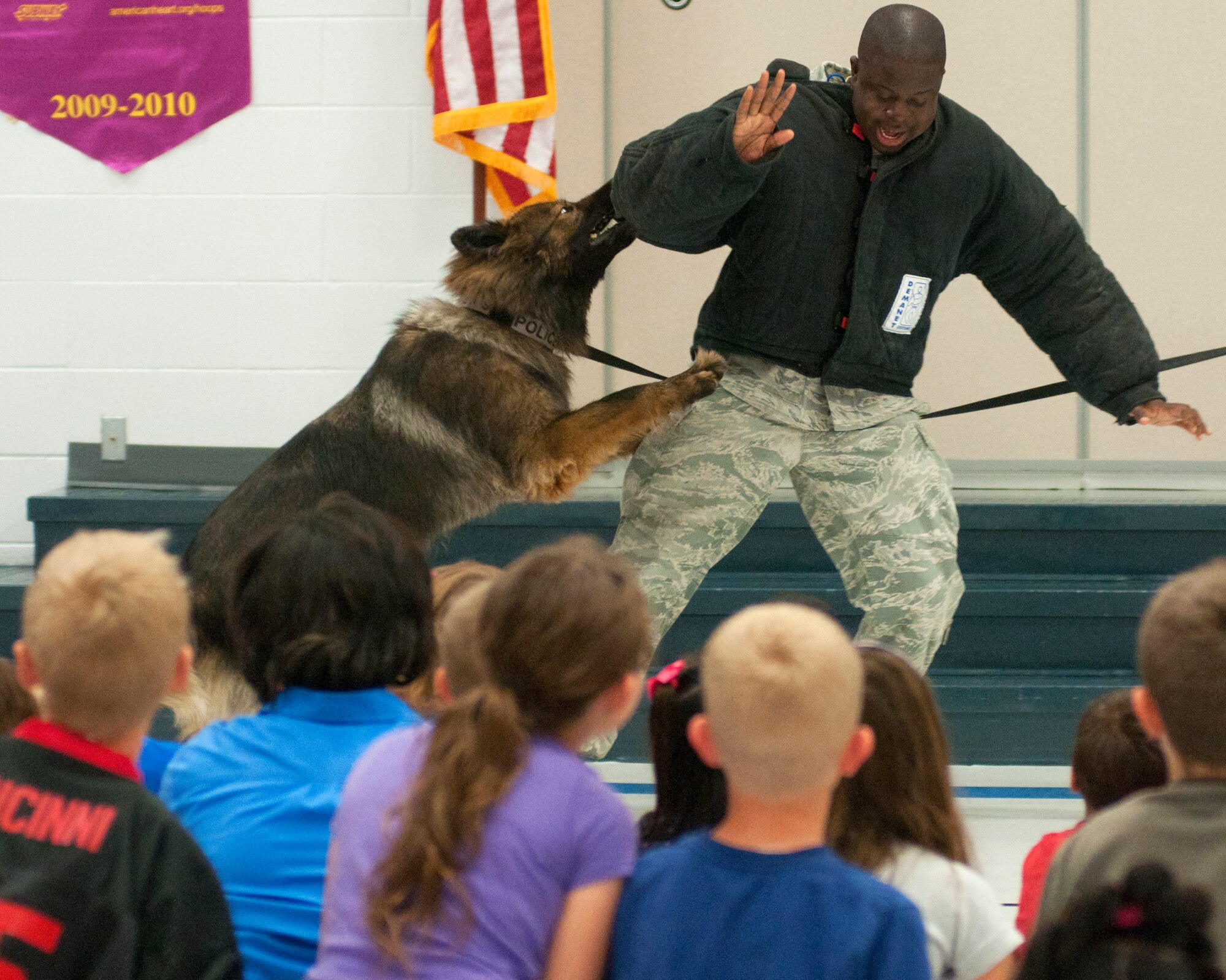 Ben, a military working dog, and Staff Sgt. Zerrick Shanks, 90th Security Forces Squadron dog trainer, demonstrate working dog training for Freedom Elementary School students Sept. 3, 2013.  A group of F.E. Warren Air Force Base Airmen visited the school to take part in an anti-bullying assembly. (U.S. Air Force photo by R.J. Oriez) 