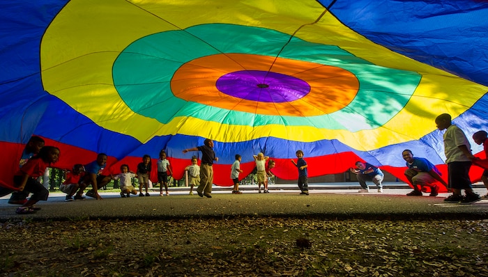 Joint Base Charleston Airmen lift up a parachute alongside school children during the Military Day of Caring volunteer event Sept. 6, 2013, at Lambs Elementary School, Charleston, S.C. Approximately 2,500 service members from JB Charleston participated in the Day of Caring, volunteering their skills to assist with more than 50 projects in the local community. The base held their volunteer events a week earlier than Trident United Way's Day of Caring, due to events surrounding the delivery of the final U.S. Air Force C-17 Globemaster III.  (U.S. Air Force photo/ Senior Airman George Goslin)