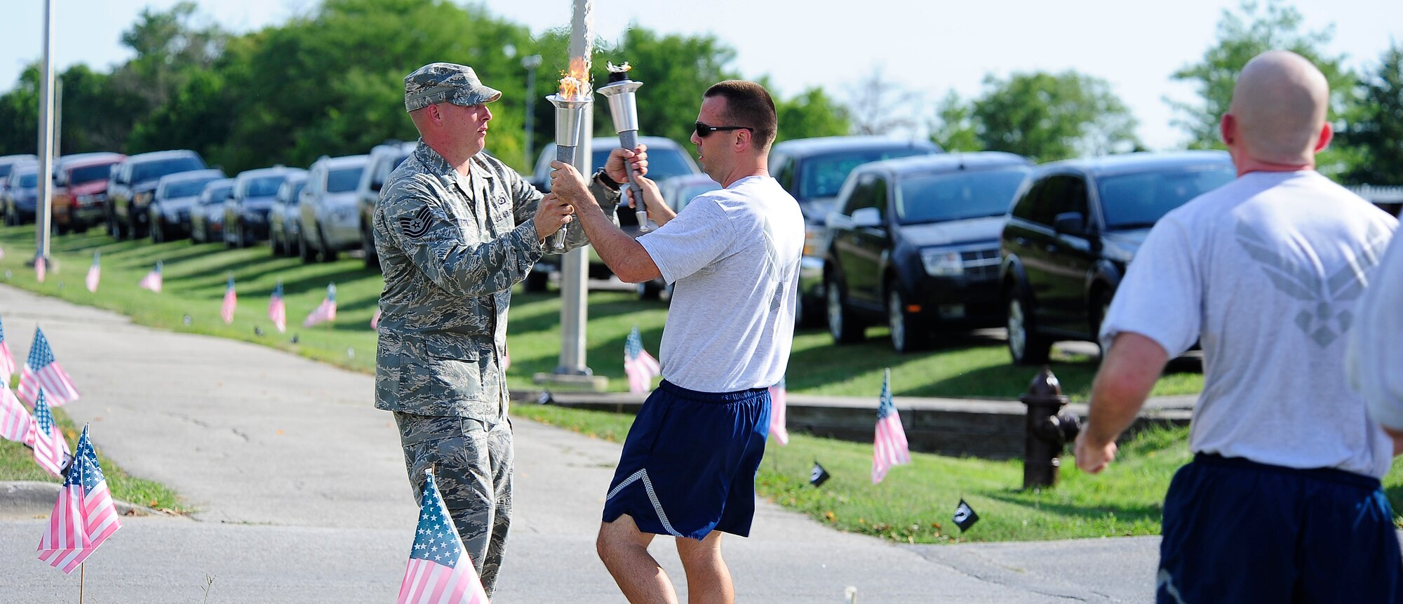 U.S. Air Force Maj. William Gibson, left, 509th Comptroller Squadron commander, grabs a lit torch from an event organizer during a prisoner of war and missing in action remembrance ceremony Sept. 5, 2013, at Whiteman Air Force Base, Mo. There are a total of 83,345 POW/MIA unaccounted for from past conflicts. (U.S. Air Force photo by Staff Sgt. Brigitte N. Brantley/Released)