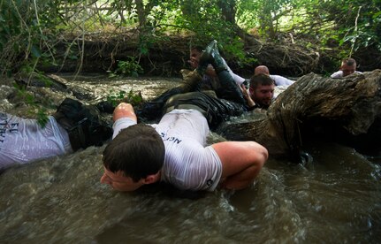Steven McDonald (center) low crawls through a creek during Rescue Athlete training Aug. 24 at Joint Base San Antonio-Lackland. Individuals participating in RA clinic prepare themselves for the rigors of Air Force special operations 9-week indoctrination course. (U.S. Air Force photo/Staff Sgt. Jonathan Snyder)