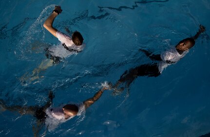 Staff Sgt. Stephaun McKinley, right, encourages his teammates Gregory Adams, left, and Chad Jureczek, top, during the Rescue Athlete training clinic Aug. 23 at Joint Base San Antonio-Lackland. (U.S. Air Force photo/Staff Sgt. Jonathan Snyder)