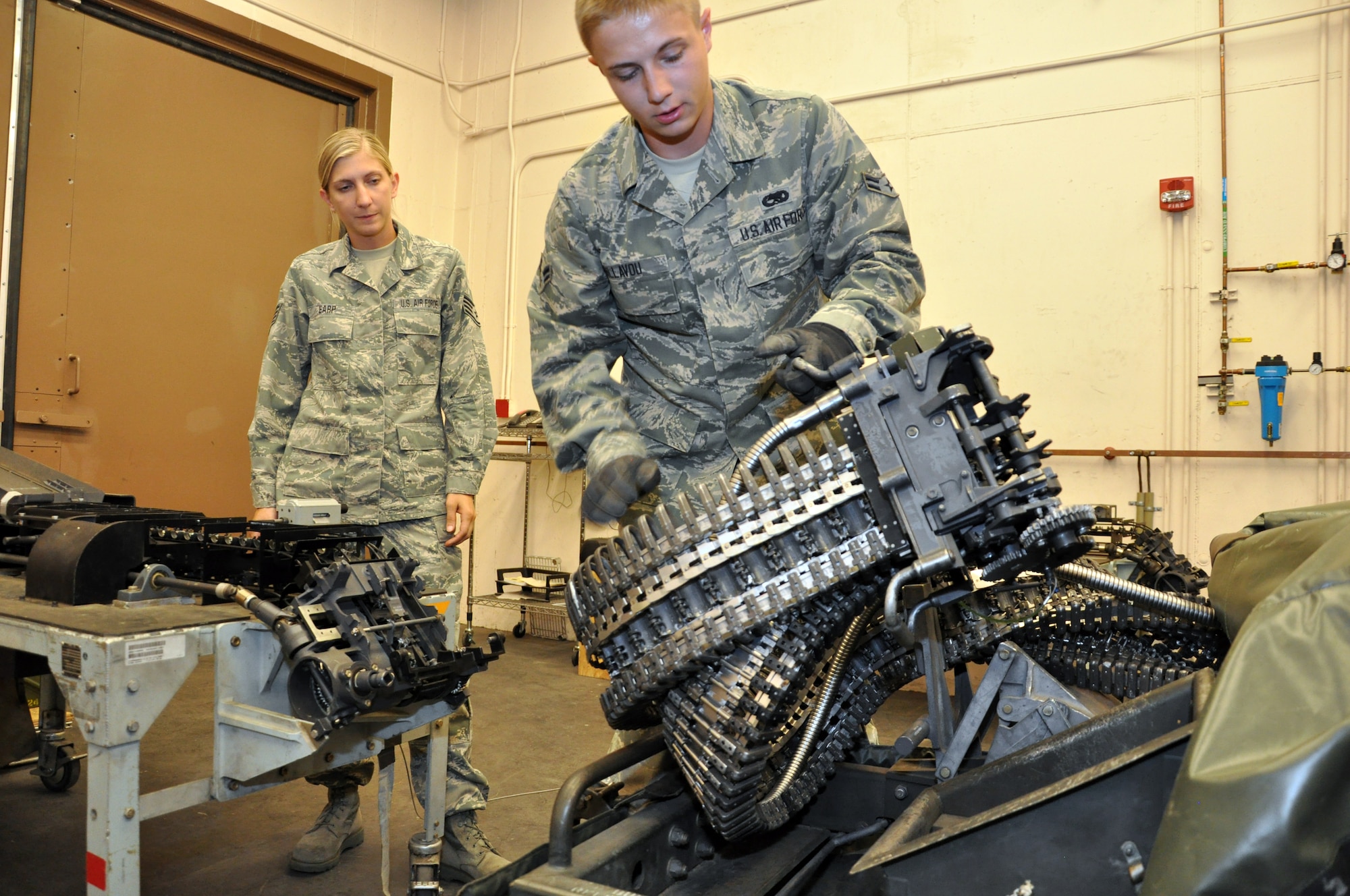 Staff Sgt. Angela Earp, 140th Wing conventional maintenance crew chief, left, supervises Airman 1st Class Cameron Dillavou, 140th Wing conventional maintenance crew member, as he lifts the adapter head of the Universal Ammunition Loading System before connecting it to the table Aug. 1, 2013, on Buckley Air Force Base, Colo.  The UALS hold 1,525 rounds of 20mm ammunition used by F-16 Fighting Falcons. The 140th Wing handles the munitions needs of units across the Front Range. (U.S. Air Force photo by Staff Sgt. Nicholas Rau/Released)