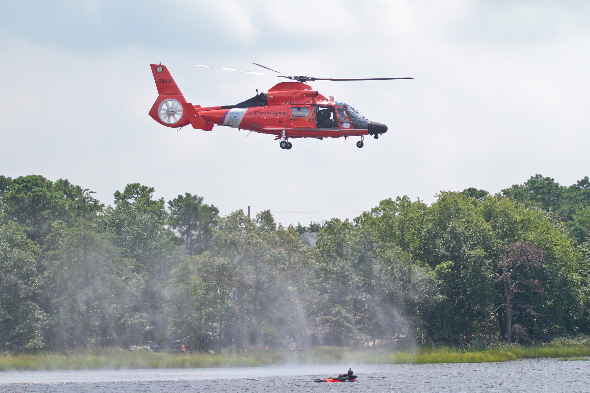 A picture of U.S. Air Force airmen and a rescue aircrew flying an HH-65C Dolphin helicopter.