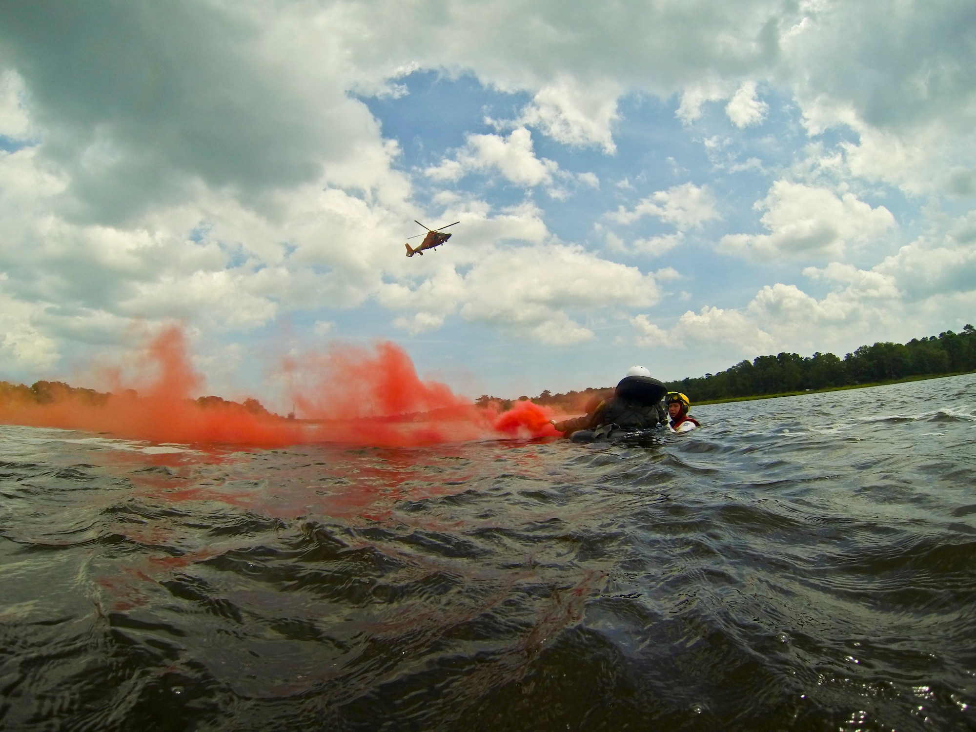 A pictureof U.S. Coast Guard rescue swimmer Jason Foyne instructing U.S. Air Force 1st Lt. Michael Gallinoto on rescue procedures as an HH-65C Dolphin rescue helicopter from Coast Guard Air Station Atlantic City approaches.