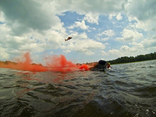 A pictureof U.S. Coast Guard rescue swimmer Jason Foyne instructing U.S. Air Force 1st Lt. Michael Gallinoto on rescue procedures as an HH-65C Dolphin rescue helicopter from Coast Guard Air Station Atlantic City approaches.