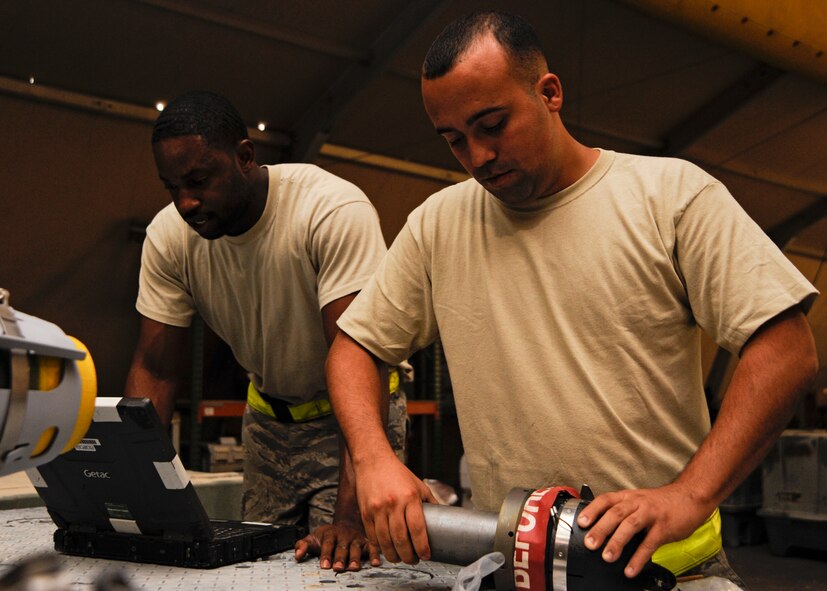 Senior Airman Jesse Bermudez places a sleeve on a laser sensor as Staff Sgt. Everett Myles reviews the technical data during a bomb build at the 379th Air Expeditionary Wing in Southwest Asia, Sept. 2, 2013. Bermudez is a 379th Expeditionary Maintenance Squadron conventional maintenance crew member deployed from Dyess Air Force Base, Texas, and a San Antonio native. Myles is a 379th EMXS conventional maintenance crew chief and hails from Fort Worth, Texas. Both are deployed from Dyess Air Force Base, Texas. (U.S. Air Force photo/Senior Airman Bahja J. Jones) 