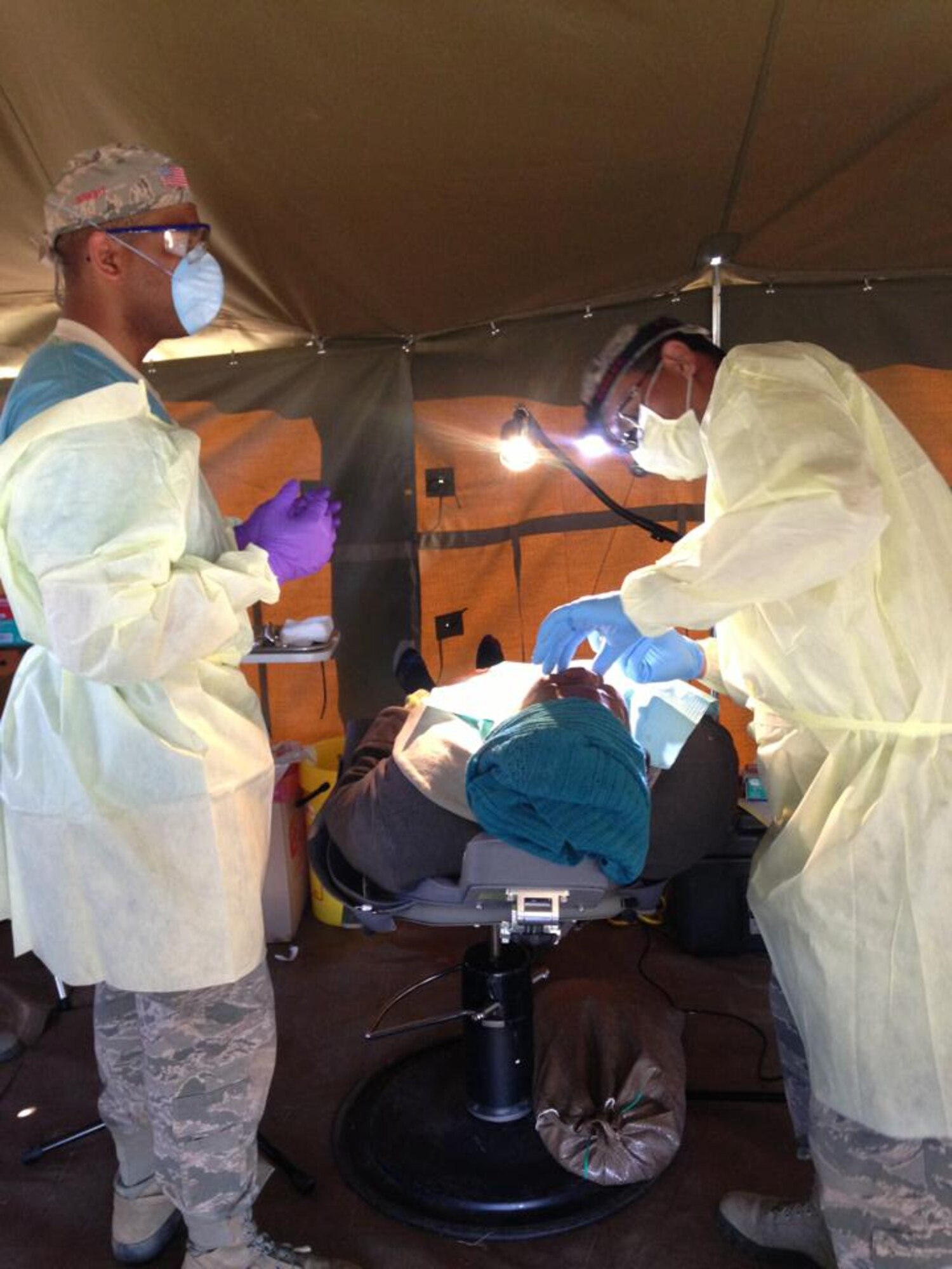 Tech. Sgt. Rowan Strong (left), 31st Dental Squadron clinical flight chief, assists during a dental procedure while on a humanitarian mission, July 21 to Aug. 8, 2013, near King Williams' Town, Eastern Cape province, South Africa.  During the humanitarian civic action event, the Airmen worked with South African dentists, providing 799 dental care procedures to more than 500 patients. (Courtesy photo) 