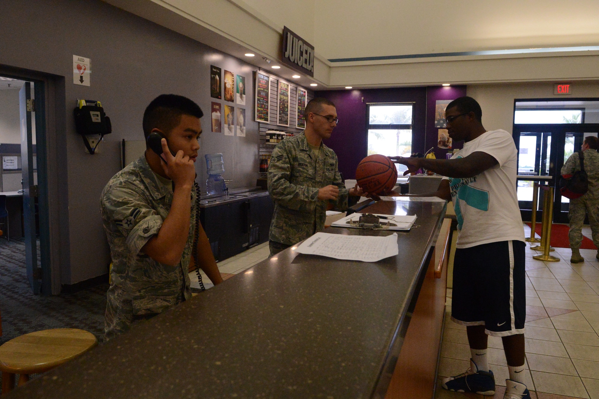 (From right) Airman 1st Class Andrew Jampathong, 36th Force Support Squadron fitness specialist, helps a customer on the phone while Senior Airman Joseph Beaton, 36th FSS fitness specialist, signs out equipment to a patron at the Coral Reef Fitness Center’s control desk Sept. 6, 2013, on Andersen Air Force Base, Guam. The fitness center’s control desk is operated by fitness specialists who keep the facility running smoothly by maintaining the machines, cleaning all equipment and performing 100 percent ID checks for individuals not in uniform. (U.S. Air Force photo by Airman 1st Class Emily A. Bradley/Released)