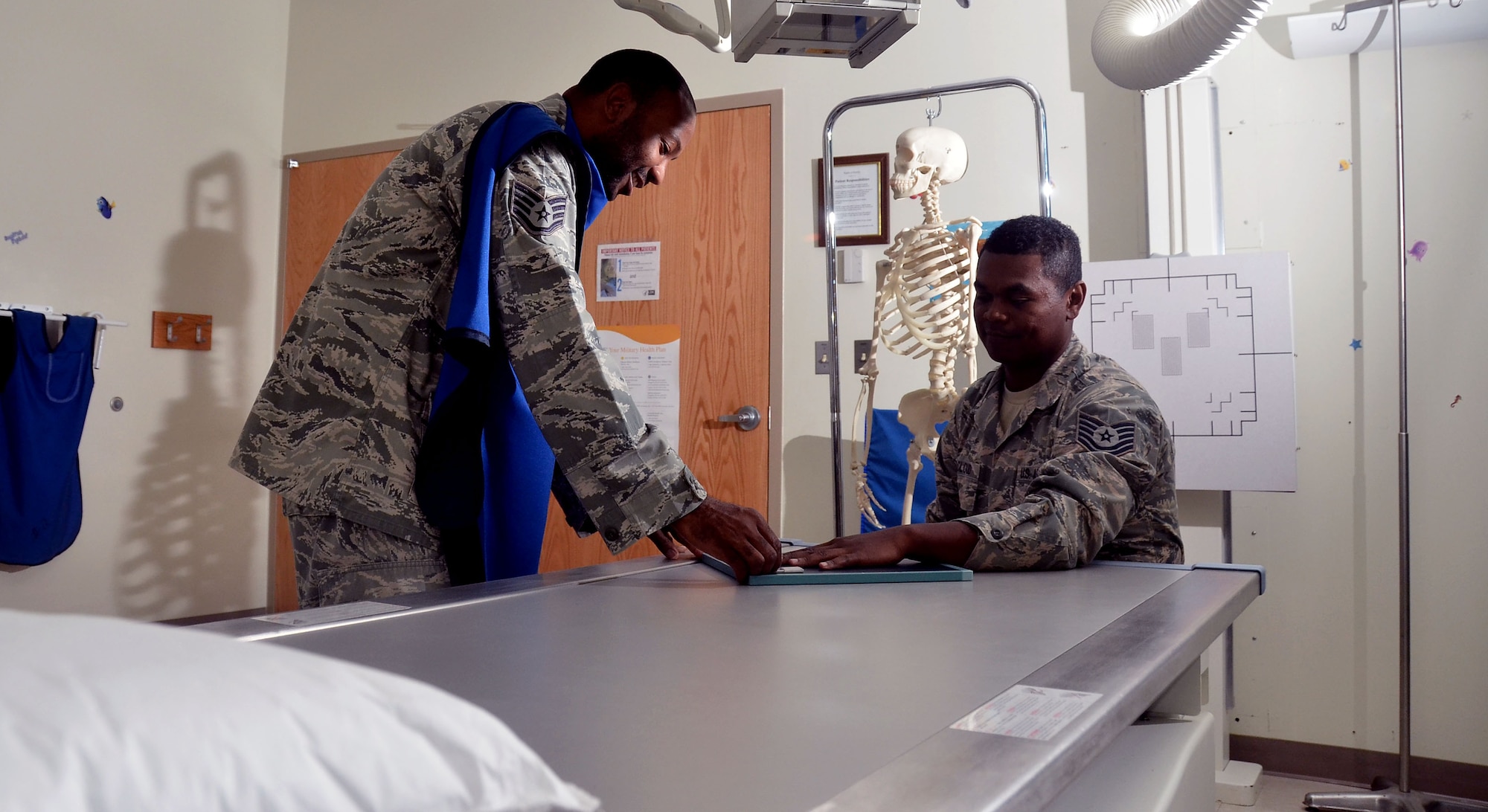 Staff Sgt. Jahmal Nicholas (left), 36th Medical Support Squadron NCO in charge of diagnostics imaging, positions Tech. Sgt. JJ McCloud, 36th MDSS diagnostic and therapeutic flight chief, for a posterior anterior hand x-ray during training Aug. 4, 2013, on Andersen Air Force Base, Guam. Andersen’s clinic performs approximately 300 x-rays a month to allow a more in-depth look into any anomalies a patient may have. (U.S. Air Force photo by Airman 1st Class Mariah Haddenham/Released)
