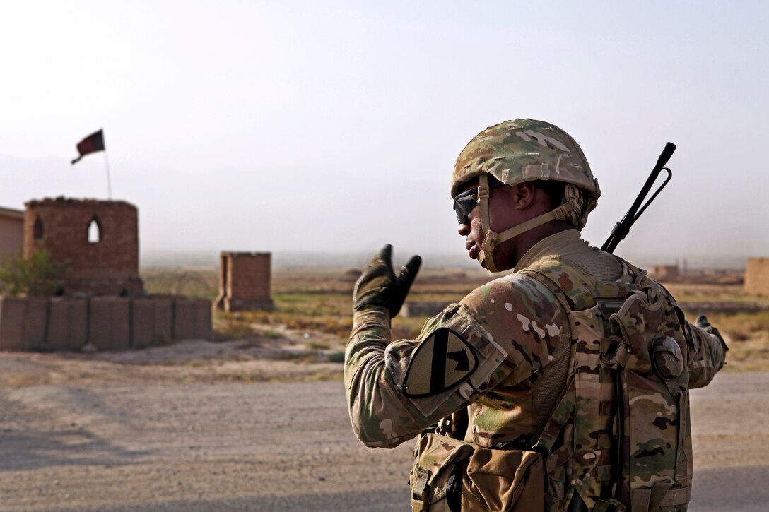 U.S. Army Pfc. Shan Lawrence directs the flow of traffic during an entry control stop across from the Afghan national police station in Qarabagh, Afghanistan, Aug. 24, 2013. Lawrence is assigned to 3rd Battalion, 82nd Field Artillery Regiment. 