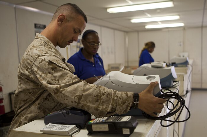 Sgt. Adam Burr, a Grand Rapids, Mich., native and dispatch chief with Combat Logistics Regiment 2, Regional Command (Southwest), at the post office aboard Camp Leatherneck, Afghanistan, installs the new Pitney Bowes meter and scale Sept. 1, 2013. The postal clerks at Camp Leatherneck were the first Marines to utilize the new meter and scale system in a deployed environment.