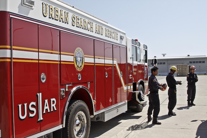 Firefighters from Marine Corps Air Station Iwakuni, Japan, prepare to suit up for their practical application exam during the Urban Search and Rescue Technical Search Training course Aug. 27, 2013.