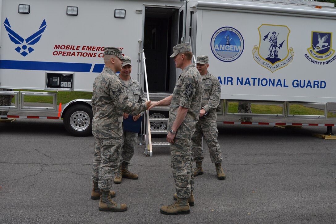 Chief Master Sgt. of the Air Force James A. Cody (second from right) toured the 174th Attack Wing, Hancock Field on Sep. 7, 2013. Cody visited Hancock Field to meet with Airmen, get the pulse of the enlisted force and answer questions. Staff Sgt. Stephen Bitler (left) who works with the Mobile Emergency Operations Center was presented a coin by CMSAF Cody. (Photo by New York Air National Guard Tech. Sgt. Justin A. Huett)