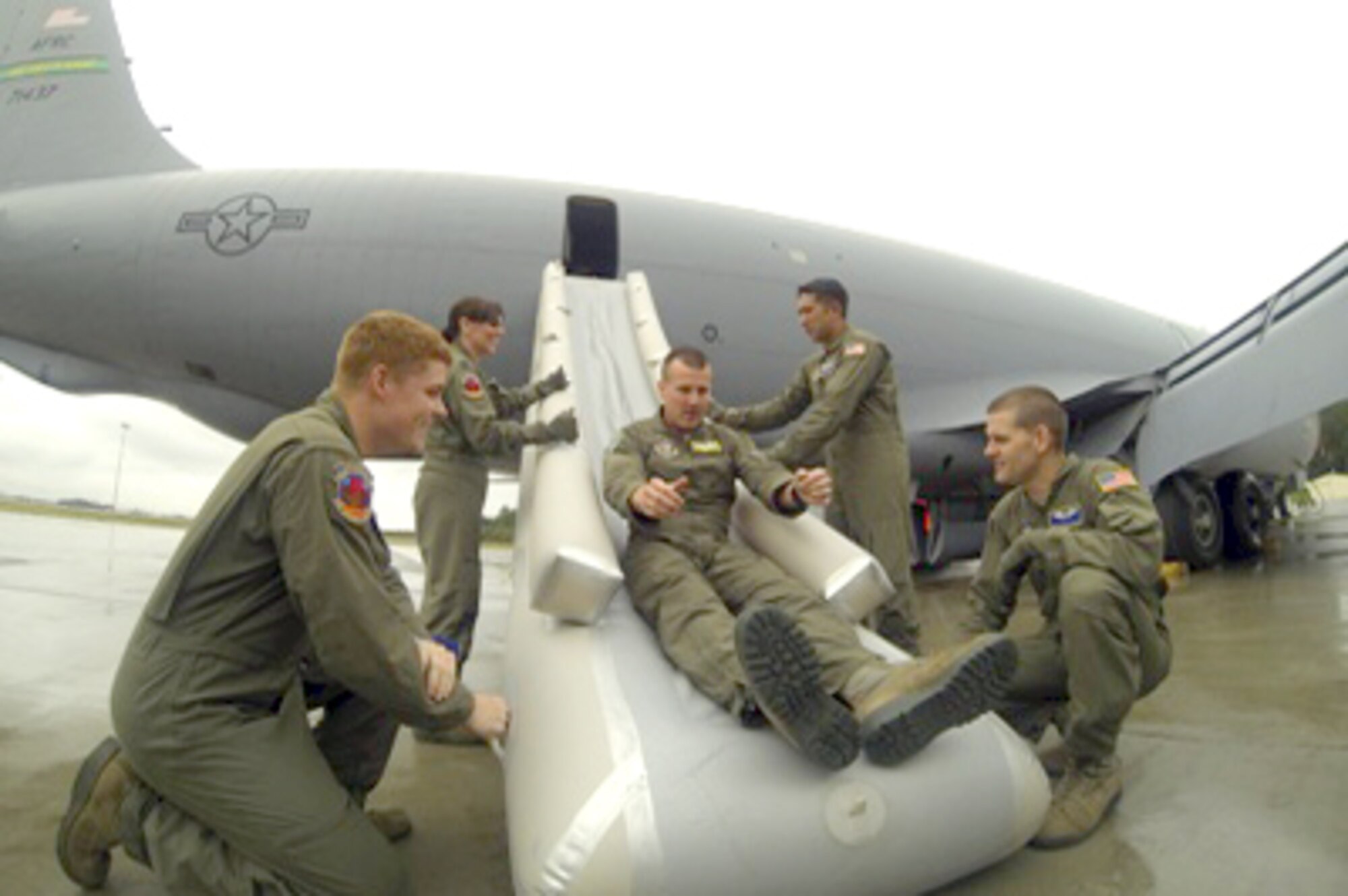Members of the 36th Aeromedical Evacuation Squadron assist Staff Sgt. Jeremy Bennett, 916th boom operator, as he egresses the aircraft on an escape slide. KC-135R Stratotanker emergency escape procedures were part of the 36th AES training held in Anchorage, Alaska in August. (USAF photo by Master Sgt. Wendy Lopedote, 916ARW/PA)