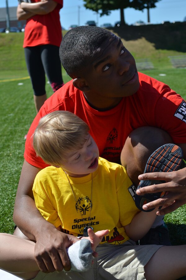 Lance Cpl. Jeremy Brown, event volunteer, helps Benjamin, 7, put on his shoe after of the Special Olympics track and field meet aboard Marine Corps Base Quantico on Sept. 7, 2013. Each athlete that participated had a personal escort to assist them through the event.