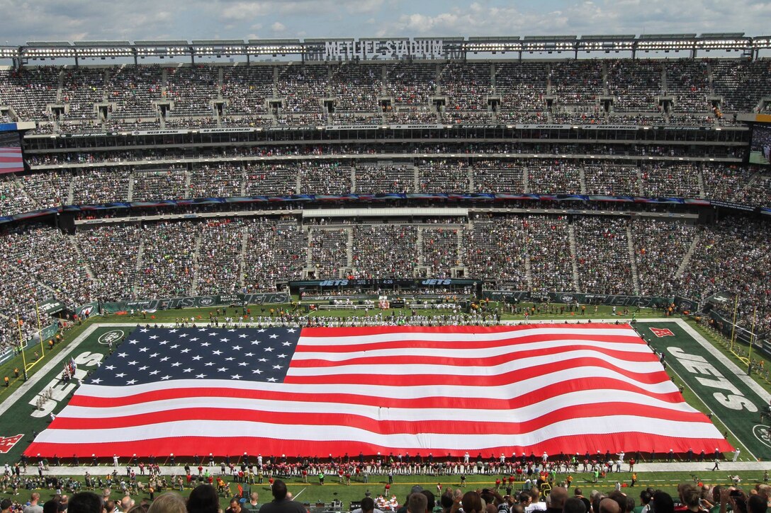 Marines assigned to the 1st Marine Corps District along with members of each branch of service unfurl the American flag during the pregame ceremony at MetLife Stadium, Sept. 8.  Five Marines from 1MCD were on the field representing the Corps during the New York Jets opening day.