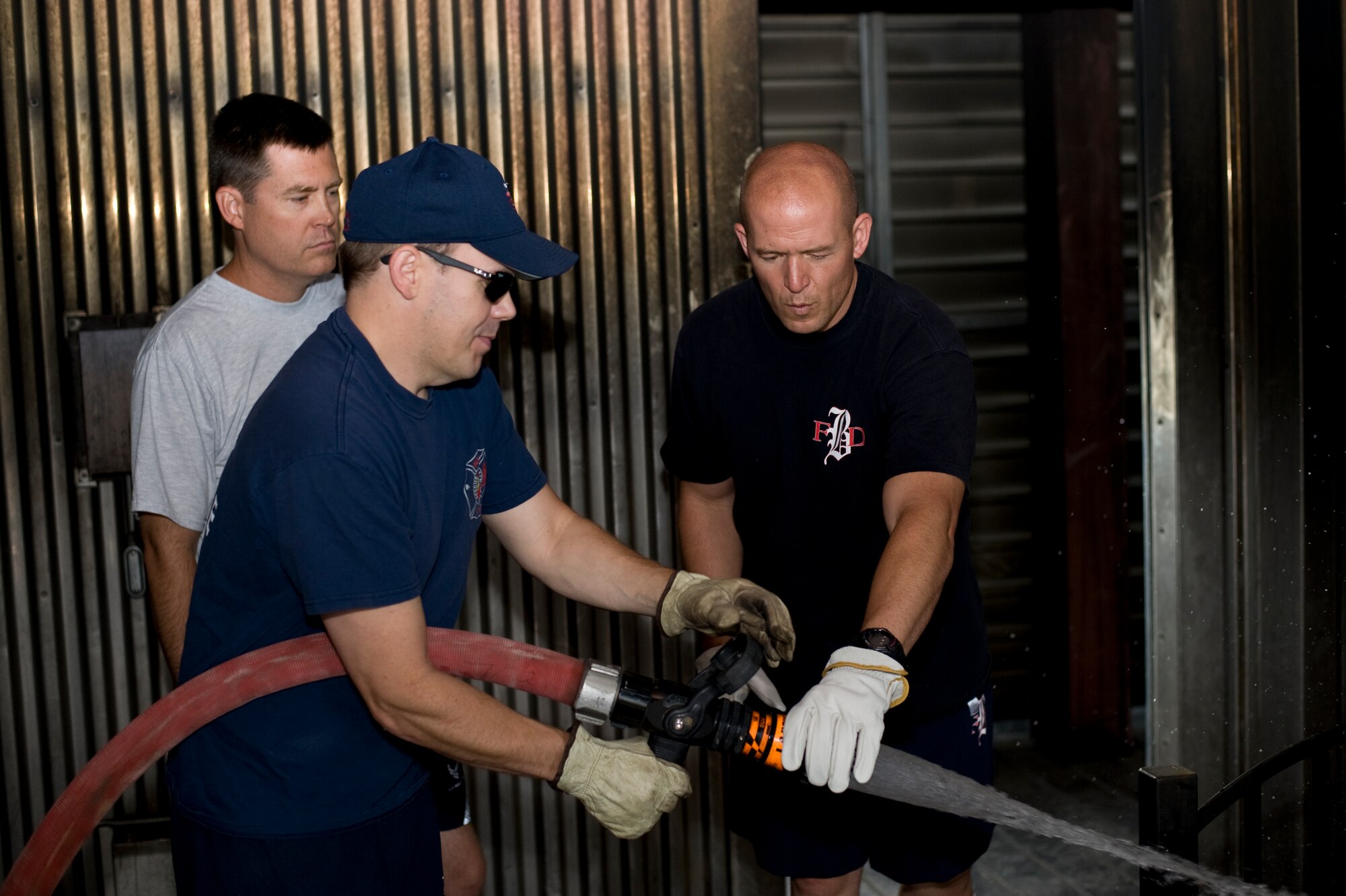 Lt. William LaRosa, Buckley firefighter, center, controls the fire hose as Jason Debord, Buckley firefighter, demonstrates its proper use to Col. Dan Wright, 460th SW commander, during a fire immersion training Sept. 5, 2013, at the Buckley fire training station on Buckley Air Force Base, Colo. Wright, as well as Chief Master Sgt. Craig S. Hall, 460th SW command chief, and Lt. Col. Allen Thibeaux, 460th Civil Engineer Squadron commander, were brought through a fire immersion scenario designed to teach them the challenges firefighters face during an emergency.  (U.S. Air Force photo by Senior Airman Phillip Houk/Released)