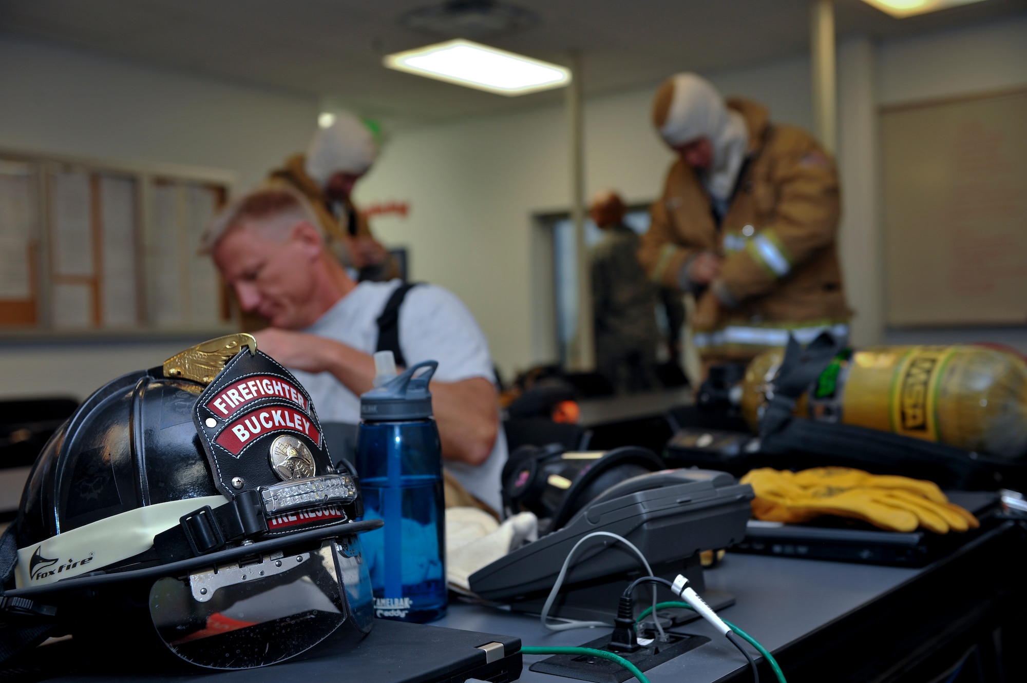 Members of the 460th Space Wing leadership practice donning firefighting gear Sept. 5, 2013, at the Buckley Fire Department on Buckley Air Force Base, Colo. Col. Dan Wright, 460th Space Wing commander; Chief Master Sgt. Craig S. Hall, 460th SW command chief; and Lt. Col. Allen Thibeaux, 460th Civil Engineer Squadron commander, were brought through a fire immersion scenario designed to teach them the challenges firefighters face during an emergency.  (U.S. Air Force photo by Senior Airman Phillip Houk/Released)