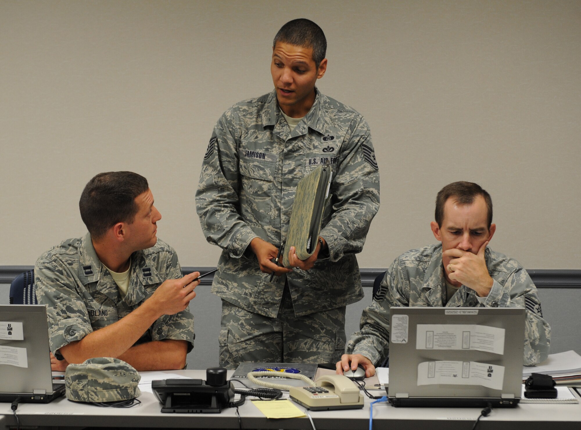 Capt. Ryan LeBlanc, left, 2nd Civil Engineer Squadron, speaks with Tech. Sgt. Shawn Jamison, center, 2nd Civil Engineer Squadron emergency management, as Tech. Sgt. Rick Cook, right, 2nd CES EM, stays up-to-date on the current training incident at the Emergency Operations Center on Barksdale Air Force Base, La., Sept. 5, 2013. LeBlanc took over as the EOC director, who is in charge of the EOC, and acted as a liaison to the Crisis Action Team. (U.S. Air Force photo/Senior Airman Benjamin Gonsier)