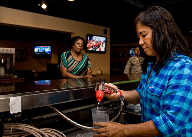 Normi West, Time Out Sports Lounge cashier, fills a glass with water for Janice Burden, Desert Oasis barber, Sept. 6, 2013, at Nellis Air Force Base, Nev. The Time Out Sports Lounge airs all pay-per-view sporting events. It is located in Bldg. 324 across from One Nevada Credit Union on Griffis Ave. (U.S. Air Force photo by Airman 1st Class Jason Couillard)