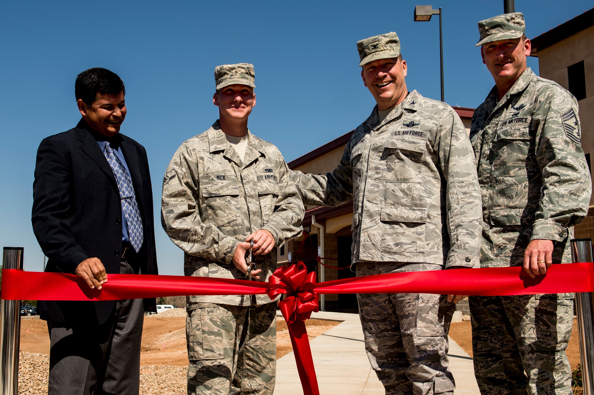 U.S. Air Force Col. Tony Bauernfeind, 27th Special Operations Wing commander, and Chief Master Sgt. Paul Henderson, 27 SOW command chief, stand with Airman Zachariah Mick, 27th Special Operations Maintenance Squadron, and John Moreno, U.S. Army Corps of Engineers, Albuquerque, N.M., division chief of engineering and construction, prepare to cut the ribbon on a new dormitory for Air Commandos Sept. 6 at Cannon Air Force Base, N.M. The $12.4 million construction project was initiated in April 2012 and is based on the Air Force's Dorms-4-Airmen concept. The building boasts 96 individual rooms, each with its own private bathroom. (U.S. Air Force photo/Staff Sgt. Matthew Plew)