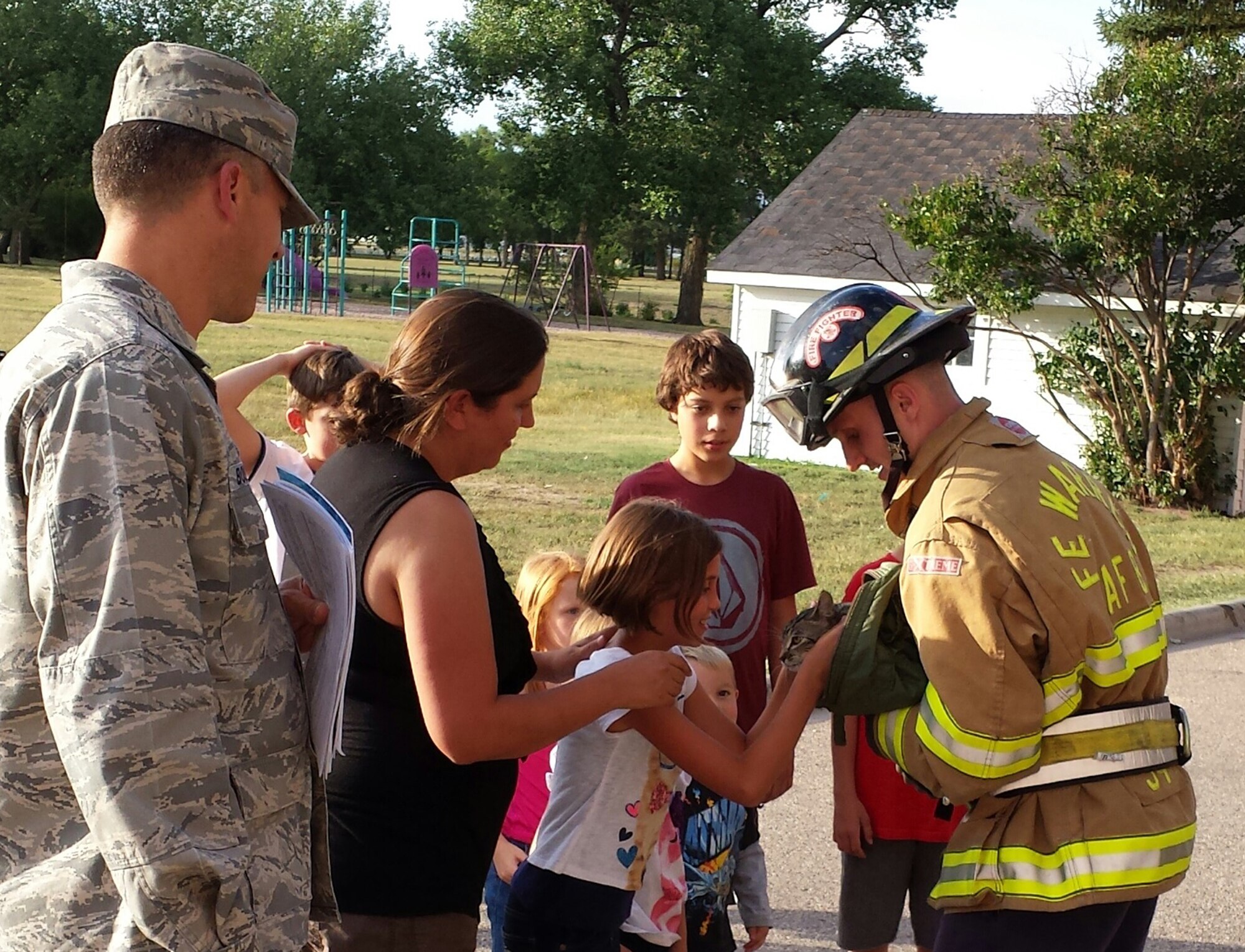 The firefighters of F.E. Warren Air Force Base, Wyo., made a special house call to rescue a cat from a tree Aug. 27, 2013. Senior Airman Rodney Turner, 90th Civil Engineer Squadron firefighter, returns Max to his owner Elizabeth Marvin, 9. Turner climbed to a height of about 60 feet in order to rescue the cat from the tree. The Fire department took this as an opportunity to practice ladder training while providing a community service. (U.S. Air Force photo by Maj. John Dines)
