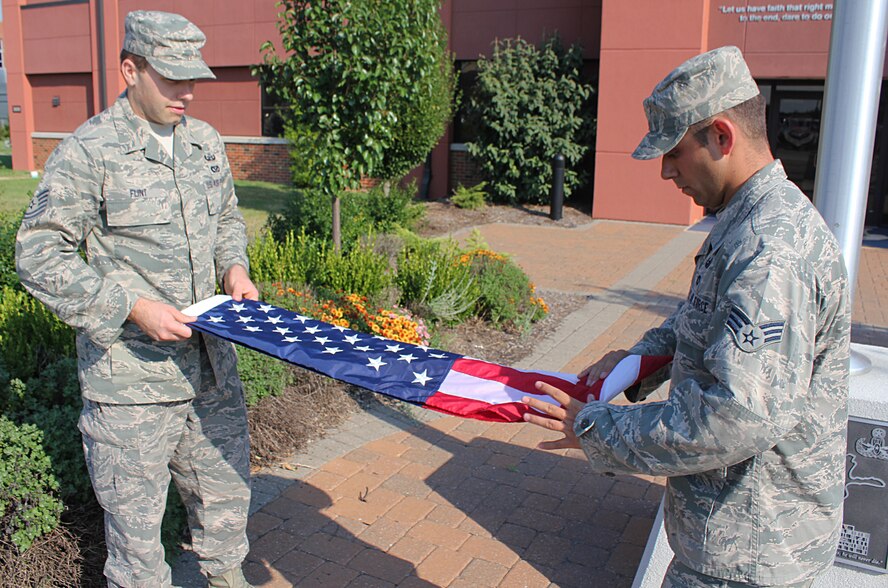 Tech. Sgt. Brock Flint (left) and SrA. Christopher Priddy from the 932nd Civil Engineer Squadron’s (CES) Explosive Ordnance Disposal (EOD) unit, fold a U.S. flag on Sept. 6 in front of the 932nd Airlift Wing headquarters building. The flag will be flown on Sept. 11, 2013 at “Ground Zero,” in New York City and is being flown in honor of Tech. Sgt. Anthony Campbell, a 932nd CES/EOD member who was killed in action in December 2009. The flag will be returned to the 932nd Airlift Wing after the Sept. 11 event. (U.S. Air Force photo/MSgt. Gerald Sonnenberg)