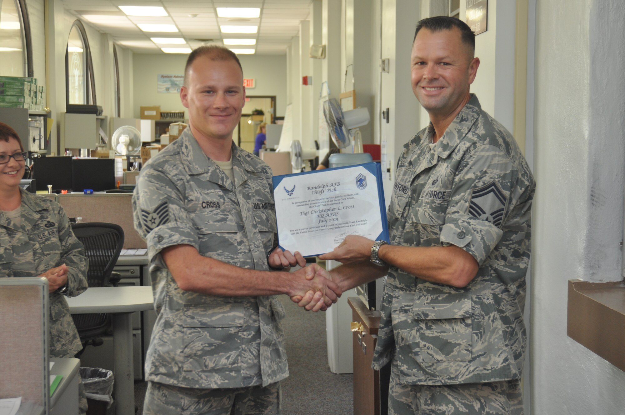 Tech. Sgt. Chris Cross, Air Force Recruiting Service knowledge operations manager (left), is presented with a Chief's Pick certificate and chief's coin from Senior Master Sgt. Steve Crawford, Joint Base San Antonio Chiefs' Group vice president, for his outstanding work and professionalism during the month of July. The Chief's Pick is presented to an Airman who demonstrates exceptional leadership, excellence and customer service. Cross was nominated and selected for his support of a critical AFRISS-TF workshop. AFRISS-TF is a single integrated recruiting system used in managing the recruiting process for Regular Air Force, Air National Guard and Air Force Reserve recruiters worldwide. His support enabled all three air components and the development team to work in a collaborative environment that would not have been possible without his support. Crawford is a chief selectee. (U.S. Air Force photo/Staff Sgt. Hillary Stonemetz)
