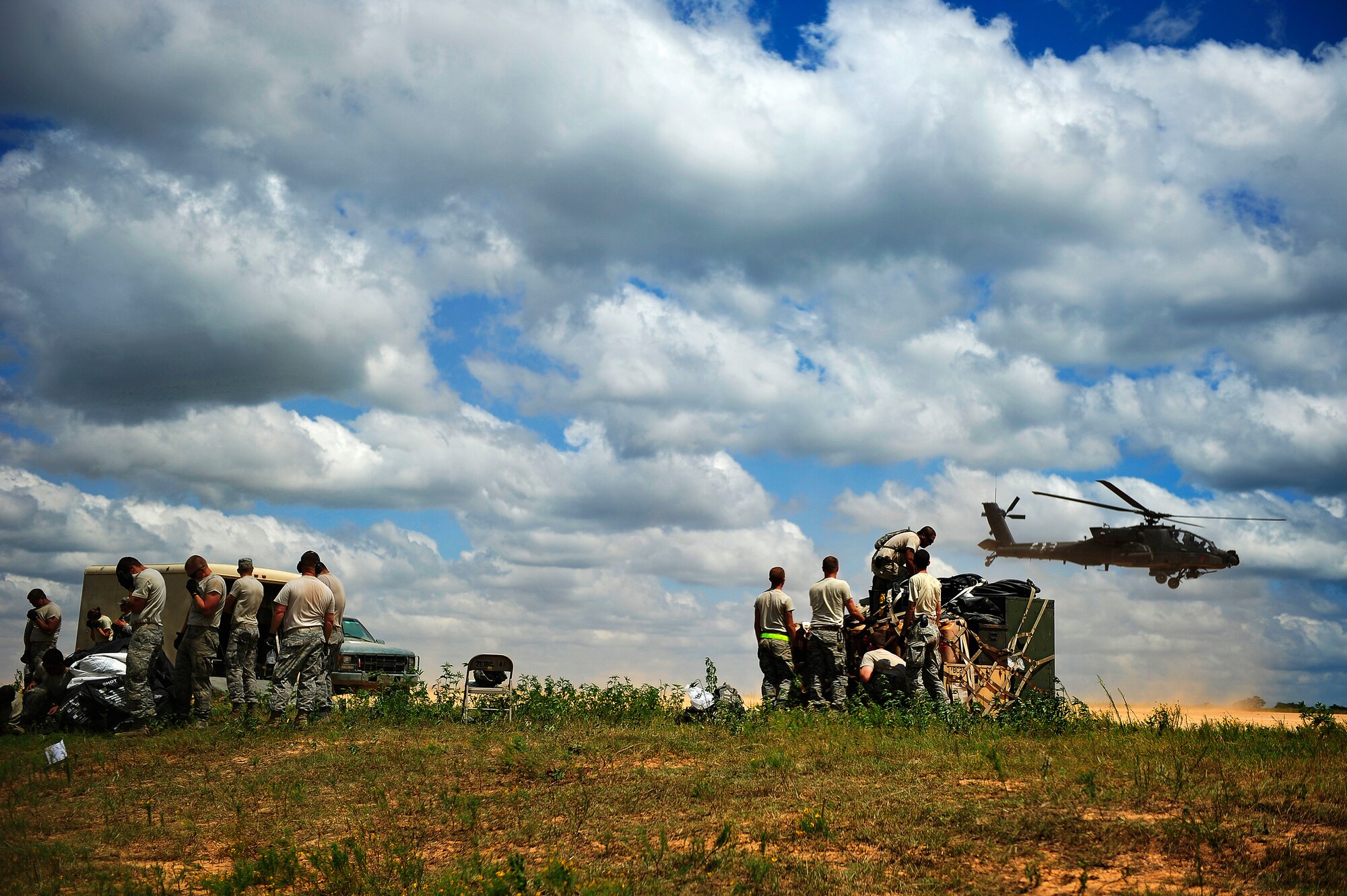 FORT POLK, La. – U.S. Air Force Airmen assigned to the 621st Contingency Response Wing, Travis Air Force Base, Calif., shelter from the dust of a departing AH-64 Apache attack helicopter as they tear down their air mobility forward support base on the edge of the Geronimo Landing Zone at Fort Polk, La. at the end of their Joint Readiness Training Center rotation 13-09, Aug. 24, 2013. The CRW specializes in rapidly establishing air mobility support operations in disaster-stricken, austere or hostile environments in response to natural disasters or combat operations.  (U.S. Air Force photo by Tech. Sgt. Parker Gyokeres)(Released)
