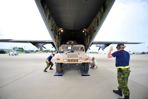 Airmen assigned to the 621st Contingency Response Wing from Joint Base McGuire-Dix-Lakehurst, N.J., work alongside Canadian Royal Air Force aerial port Airmen to load a vehicle onto a running CRAF C-130J Hercules at Alexandria International Airport, Alexandria, La. during Joint Readiness Training Center rotation 13-09, Aug. 21, 2013. The Canadian Royal Air Force provided both C-130J and C-17 Globemaster II aircraft to support the large combined forces exercise. (U.S. Air Force photo/Tech. Sgt. Parker Gyokeres)