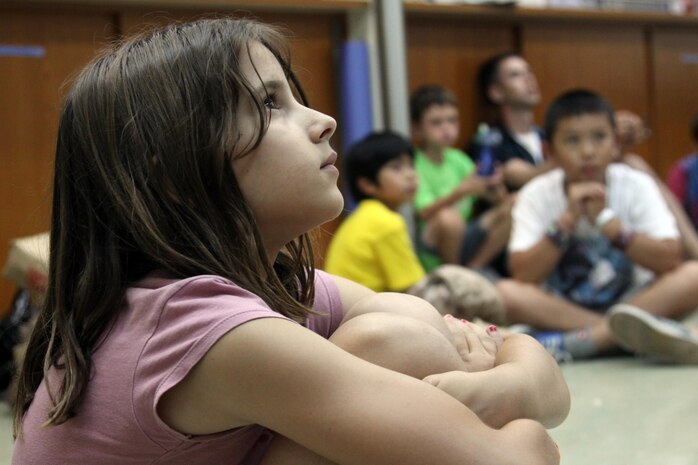 Alyssa Brickman, 9, listens to a story from the bible during Vacation Bible School aboard Marine Corps Air Station Iwakuni, Japan, Aug. 20, 2013. Many lessons are taught at VBS to help the children be more familiar with the Bible.