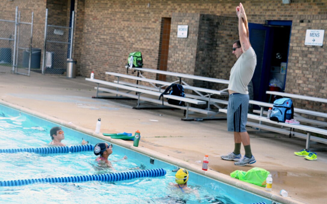 Airman 1st Class Lance Thornton coaches members of his team at practice Aug. 30. Thornton began volunteering and sharing his experience from competing at the college level in the 100-yard butterfly, 100-yard breaststroke, 50-yard freestyle, and 200-yard individual medley which he set the school record in 2009.