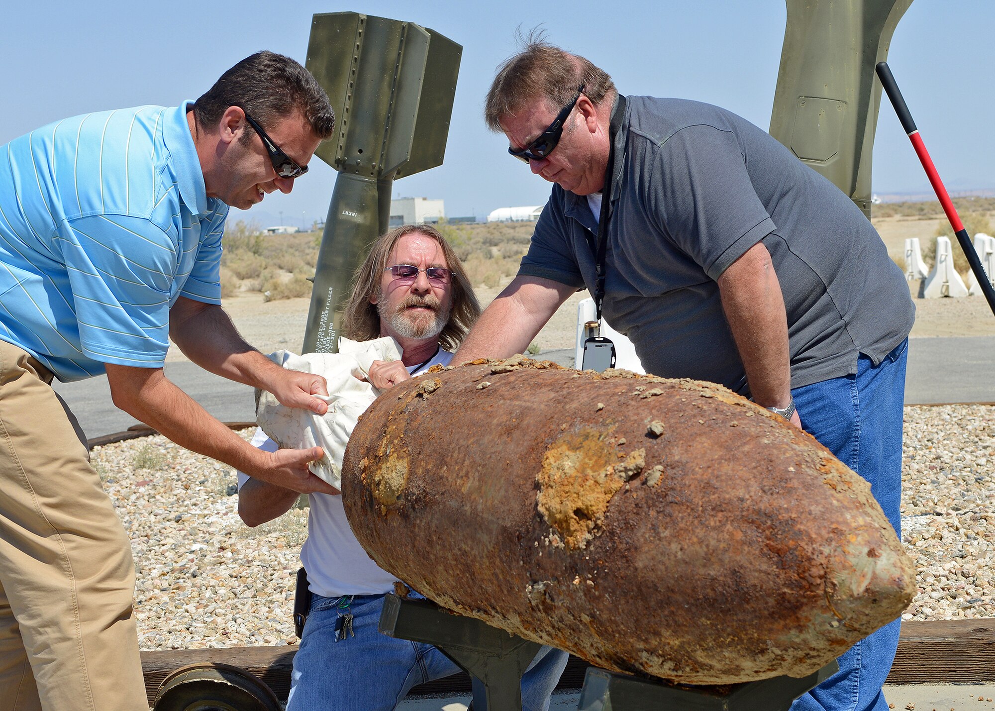 (From left to right) William Jones, Jon Wiggins and James McCaffrey remove items from a time capsule Sep. 9, in front of the 412th Maintenance Squadron Munitions Flight storage area. The time capsule was assembled and buried on Feb. 24, 1993, by all three while they were on active duty status with the then 6515th Munitions Maintenance Squadron, now civilians with 412th Maintenance Squadron. The time capsule opening was held to reveal the progression of ammo from then to now and to reflect on ammo history at Edwards. (U.S. Air Force photo by Jet Fabara)