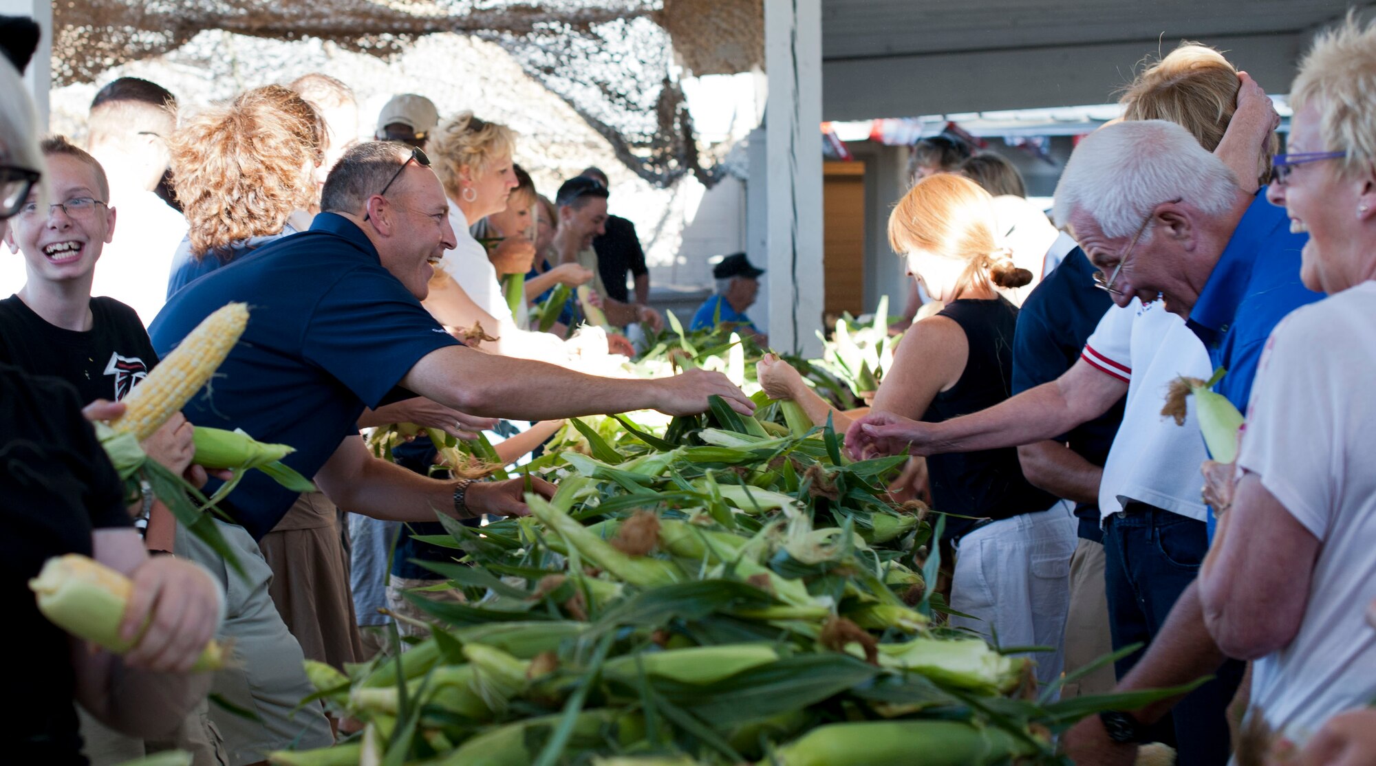 U.S. Air Force Col. Chris Short, 366th Fighter Wing commander, reaches for an ear of corn Sep. 6, 2013, at Carl Miller Park in Mountain Home, Idaho. Corn shucking is one of the first events held during the annual Air Force Appreciation Days. AFAD was started in 1961 by the Mountain Home Chamber of Commerce as a means to thank all the local military for their dedication they made to the United States. (U.S. Air Force photo by Airman 1st Class Brittany A. Chase/Released)