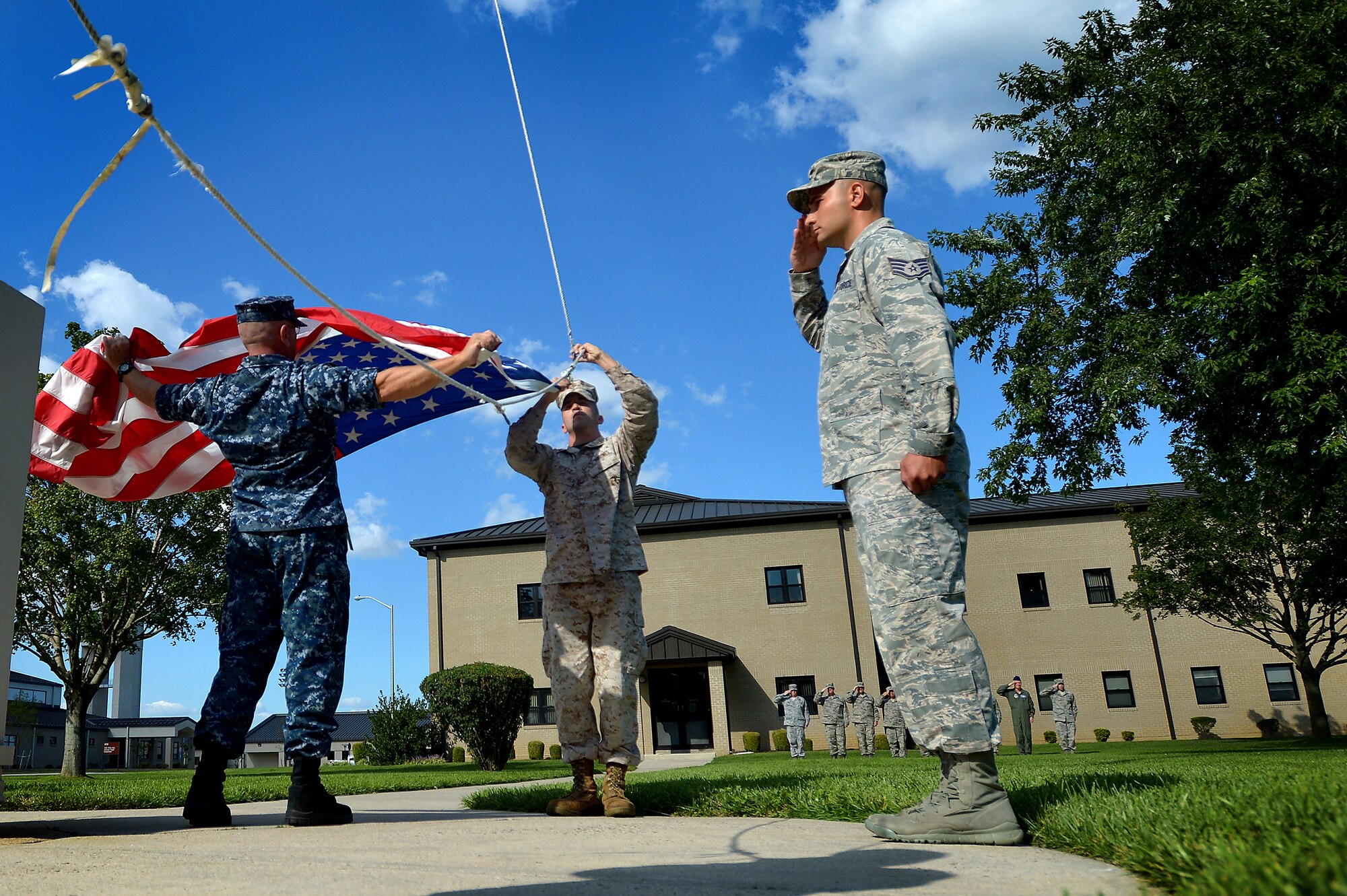 U.S. Air Force Staff Sgt. Alex Stoica, (right) renders a salute as U.S. Navy Petty Officer 1st Class Whitney Sloane, and U.S. Marine Corps Cpl. Landon Beaty lower the U.S. flag during a retreat ceremony at Dover Air Force Base, Del., Sept. 6, 2013. Stoica, Sloane and Beaty carried out each step of the ceremony along with U.S. Army Sgt. 1st Class Crystal Seymore. The four service members are assigned to Air Force Mortuary Affairs Operations. Military members from both AFMAO and the Armed Forces Medical Examiners System participated in the retreat. (U.S. Air Force photo by Staff Sgt. Kenny Holston/Released)
