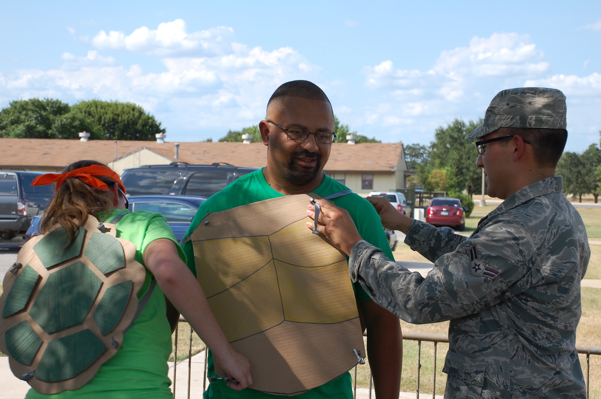 JOINT BASE SAN ANTONIO-LACKLAND, Texas -- From left, Julie Pinsinski and A1C Gilberto Rodriguez put the finishing touches on James Brown’s Teenage Mutant Ninja Turtle costume. Pinsinski and Brown, instructors with the 59th Training Squadron, decided to enter the race to because they saw it as a great team building opportunity for their students.   (U.S. Air Force photo/Debbie Aragon)