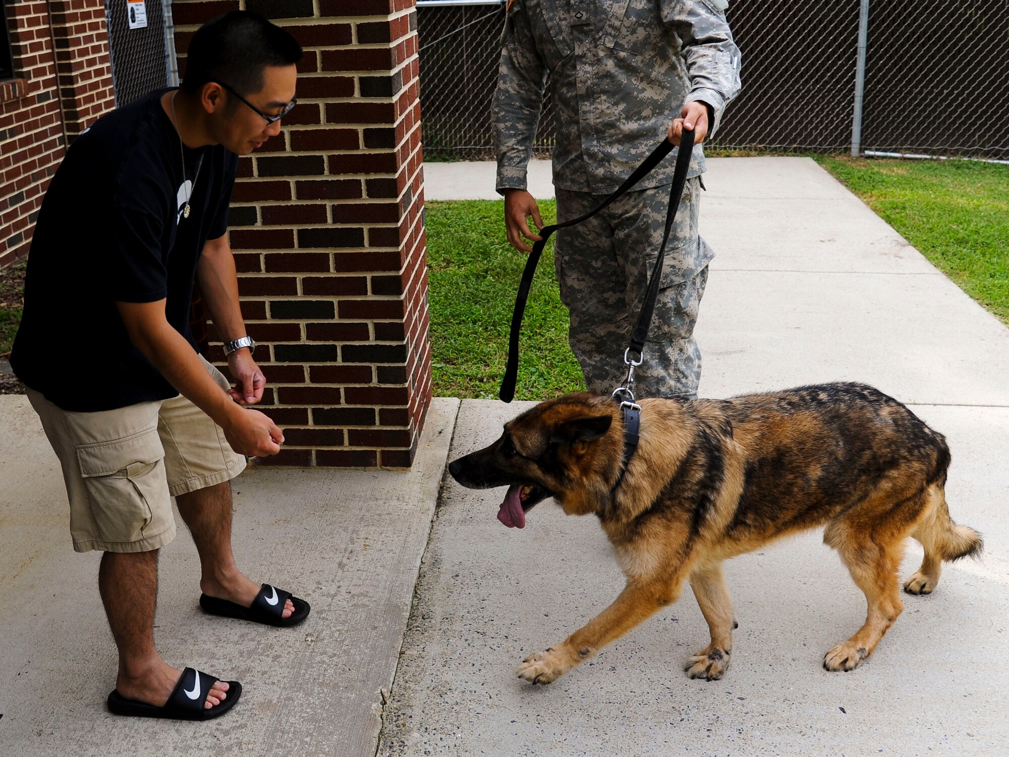 Andrew Lou, Newport News Police Department detective, receives Duuk, 3rd Military Police Detachment explosives detection military working dog, after adopting him from the Department of Defense at Fort Eustis, Va., Sept. 9, 2013. Duuk was one of the original dogs owned by the 3rd MP Det., and has been deployed to Iraq four times in his life.