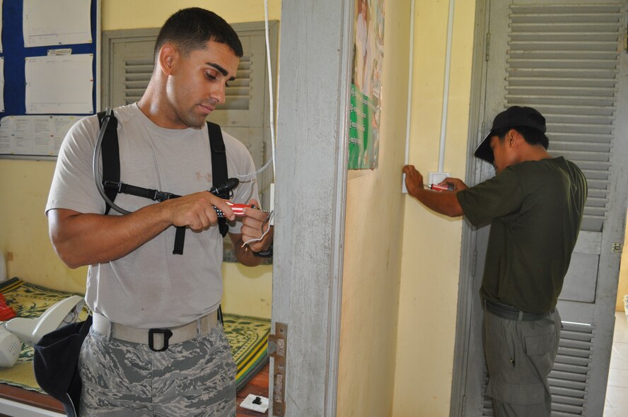 U.S. Air Force Staff Sgt. Nicholas Scheerer, electrician from18th Civil Engineer Squadron, Kadena Air Base, Okinawa, Japan, and Sgt. 1st Class Sen Khaan Khemrith, electrician from Engineering High Command, Phnom Penh, install light switches during Operation Pacific Angel 13-5 Cambodia at the health center in Nhaeng Nhang Sept. 9, 2013. Scheerer and Khemrith are working on rewiring the entire health center. This is the first day of the six-day operation. Thirty-six U.S. forces and Royal Cambodia Armed Forces worked together on three health centers during engineering civil action programs. PACANGEL is a joint and combined humanitarian assistance operation held in various countries several times a year and includes medical, dental, optometry, and engineering support programs and various subject-matter expert exchanges. (U.S. Air Force photo/Senior Master Sgt. Allison Day)